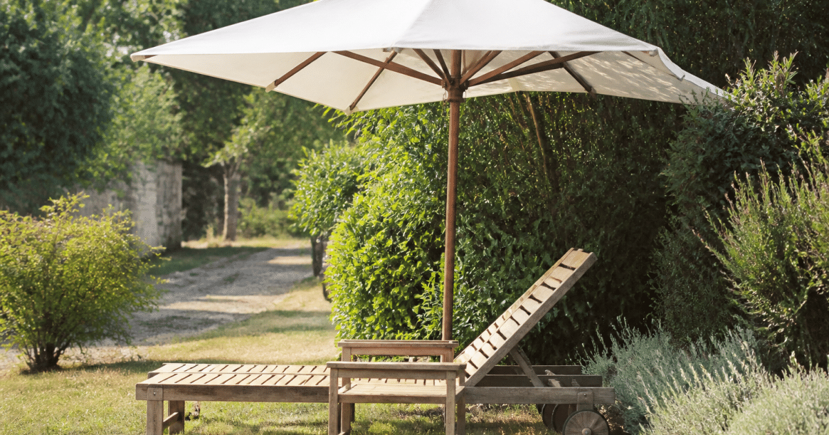 Chaise longue bois reposant sous parasol dans jardin paysage
