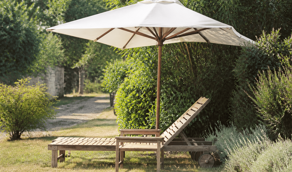 Chaise longue bois reposant sous parasol dans jardin paysage