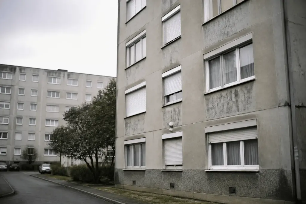 Immeubles collectifs gris avec façades usées et fenêtres fermées