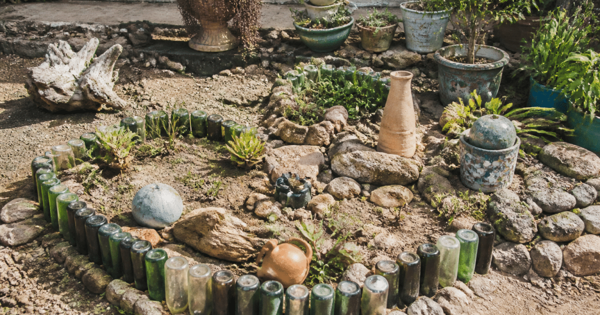 Jardin aménagé avec bouteilles, pierres et objets recyclés disposés