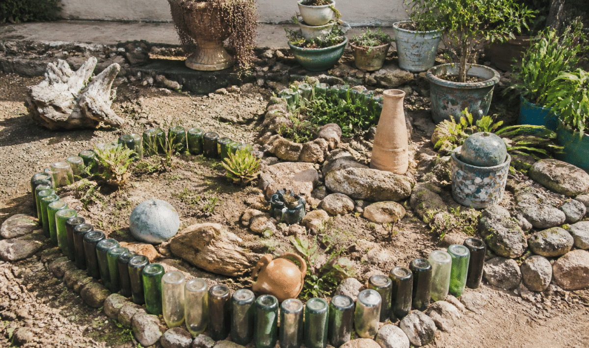Jardin aménagé avec bouteilles, pierres et objets recyclés disposés
