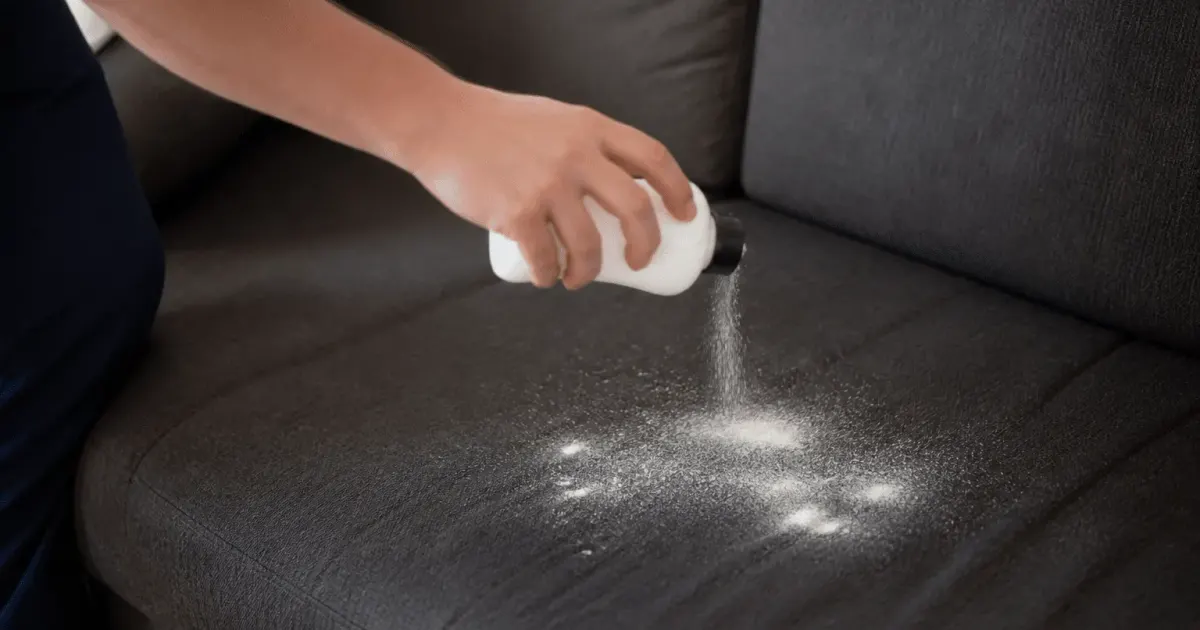 Main saupoudrant poudre blanche sur tissu canape gris
