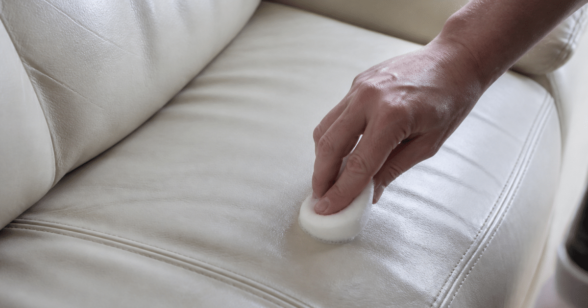 Main appliquant produit nettoyant sur coussin cuir blanc