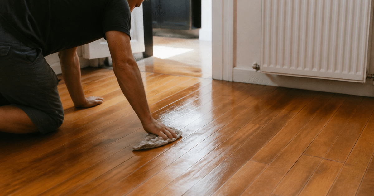 Personne appliquant liquide nettoyant sur parquet bois brillant