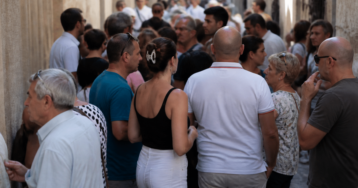 Foule de residents arlésiens debout dans rues historiques étroites