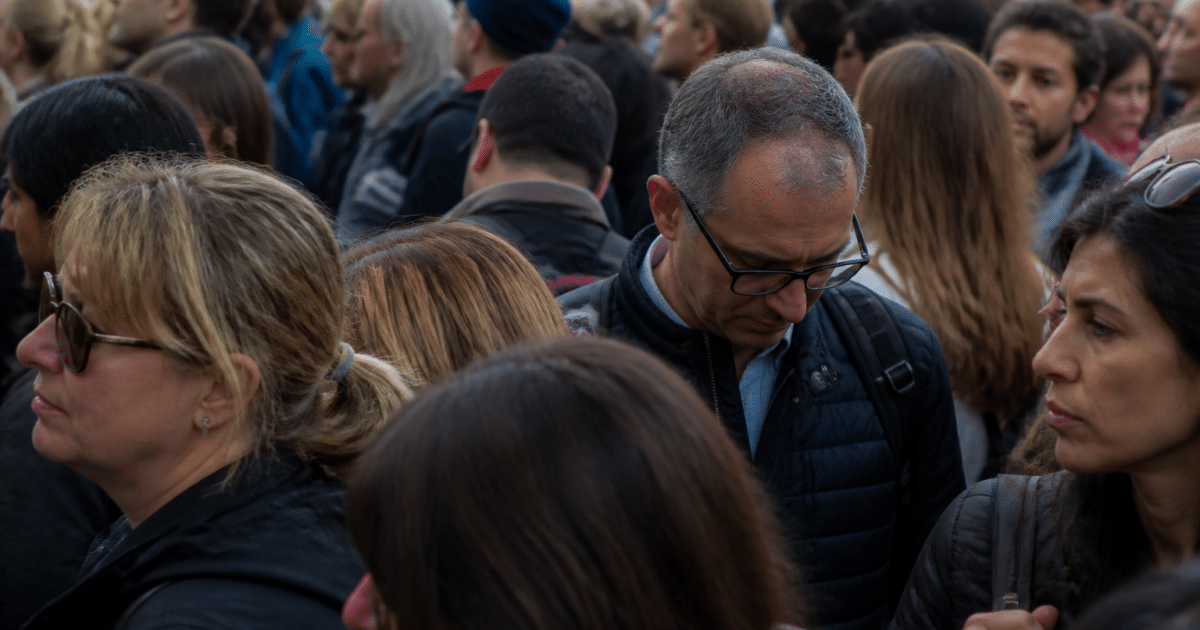 Foule de personnes debout serrées dans espace urbain dense