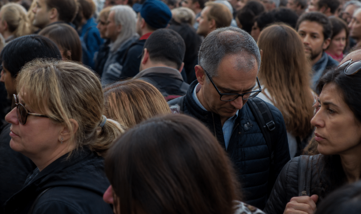 Foule de personnes debout serrées dans espace urbain dense