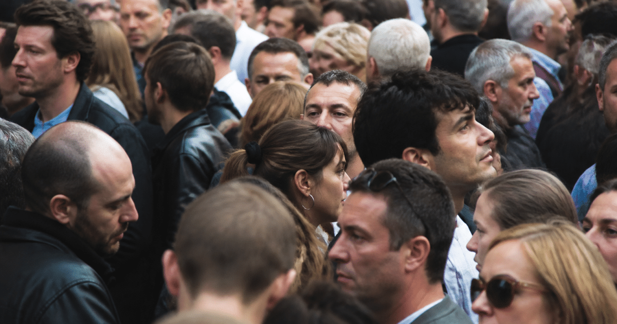 Foule dense de personnes debout serrees dans rue urbaine