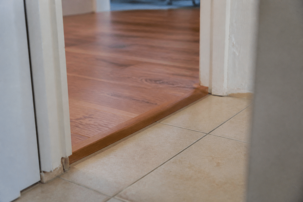 Jonction entre carrelage beige et parquet bois avec dénivellation visible