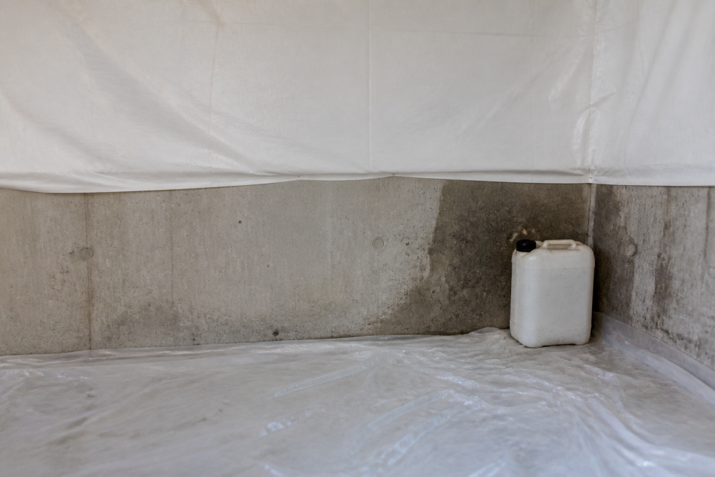 Mur gris bache blanche sol plastique bidon