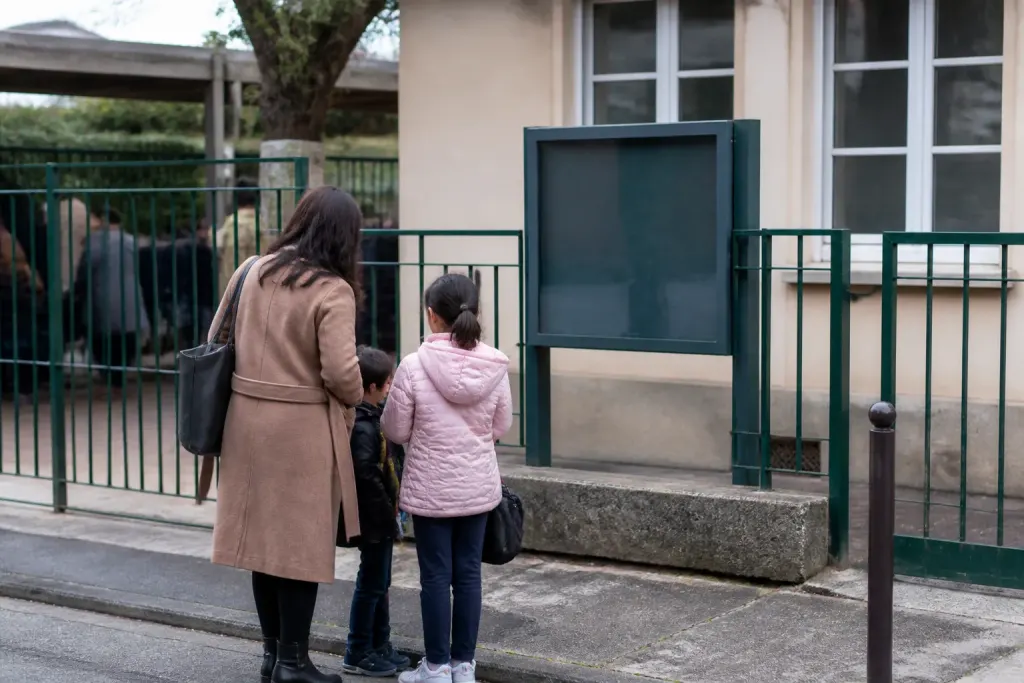 Familles devant une ecole primaire et panneau municipal