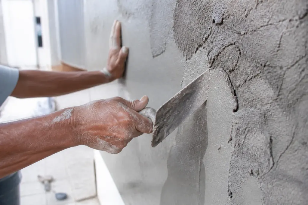 Mains tenant une truelle sur un mur