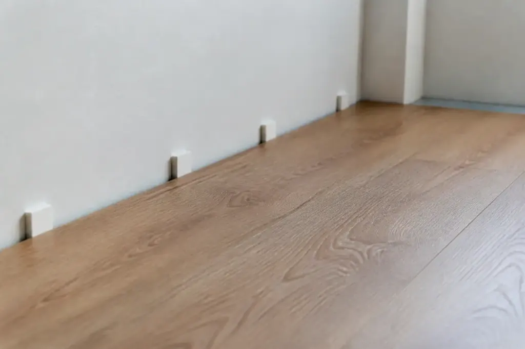 Parquet flottant avec cales blanches contre le mur
