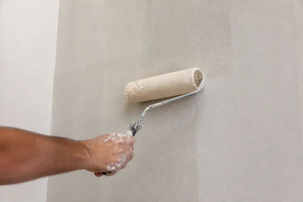Rouleau blanc etalant liquide laiteux sur mur clair